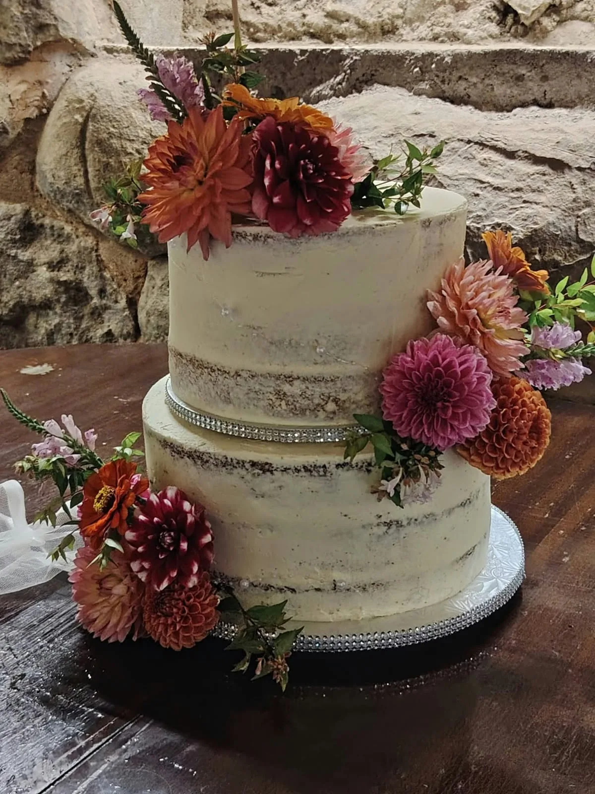Two-tier wedding cake decorated with deep red and peach flowers